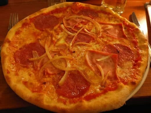 Leckere Salamipizza mit zusätzlichen Schinken und Zwiebeln im Restaurant Aposto in Berlin