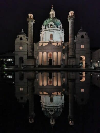 Die Karlskirche Wien spiegelt sich wunderbar bei Nacht im Wasser davor