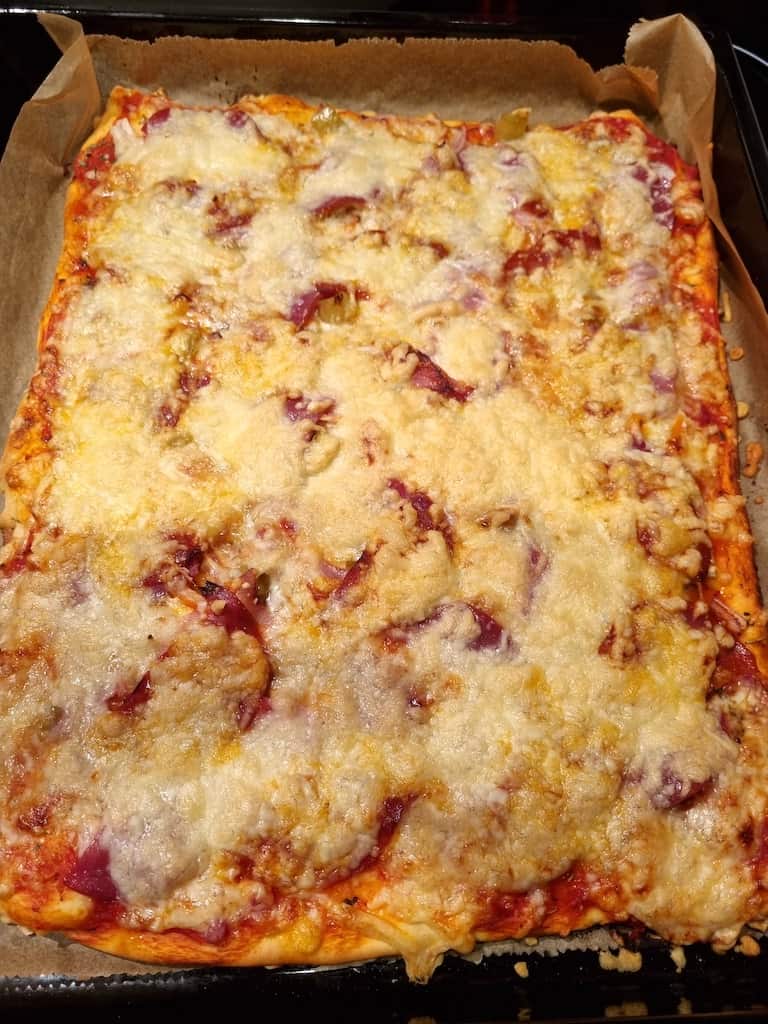 Pizza mit Schinken, Salami, Chorizo, Zwiebeln, Knoblauch und Peperoni