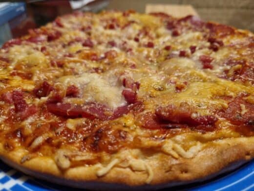 Pizza, nachbelegt mit Salami, Speck und Käse