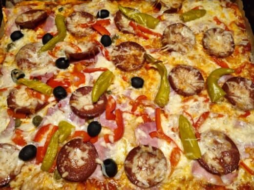 Die Pizza, dick belegt - links Nics Hälfte mit Oliven und Kapern zusätzlich