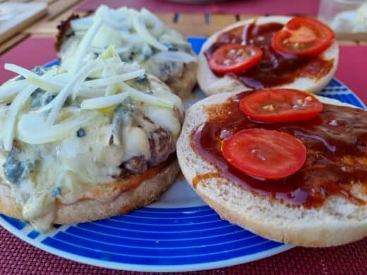 Zwei Angus Burger mit veganen Bio-Buns, Bluecheese und einer Scheiblette, dazu Tomate und Zwiebeln