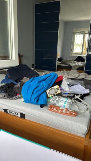 Klamotten und Technikhaufen auf dem Bett, der in den Koffer gepackt werden will