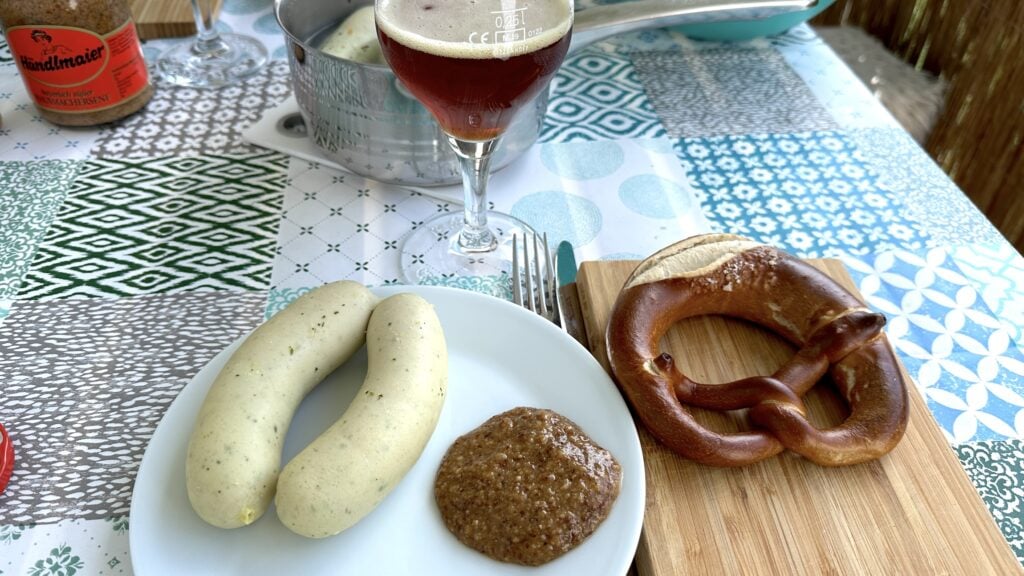 Weißwurstfrühstück mit Brezeln und süßem Senf auf dem Balkon