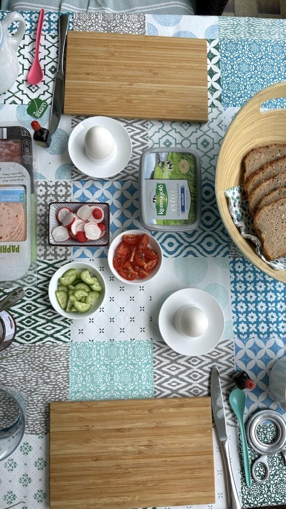 Spätstück auf dem Balkon mit Frühstücksei, Brot und Wurst, dazu etwas Gemüse