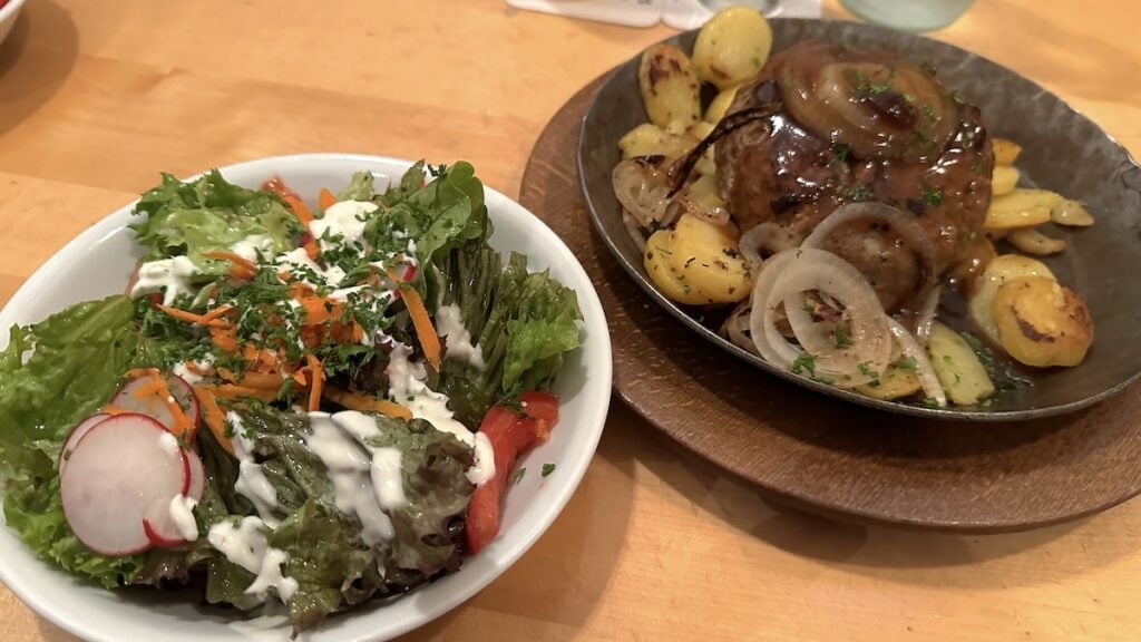 Hacksteak mit Bratkartoffeln, dazu Beilagensalat bestellt