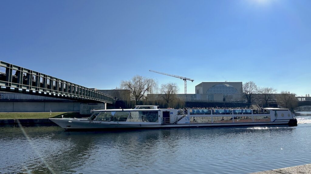 Ein Schiff tuckert vorbei, während ich am Spreeufer chille und auf den Zug warte