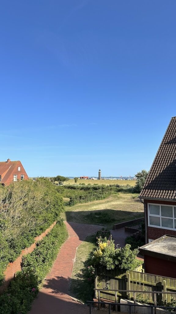 Blick vom Balkon der Ferienwohnung Fischerballje auf den Hafen Juist mit dem Leuchtturm bei strahlend blauen Himmel
