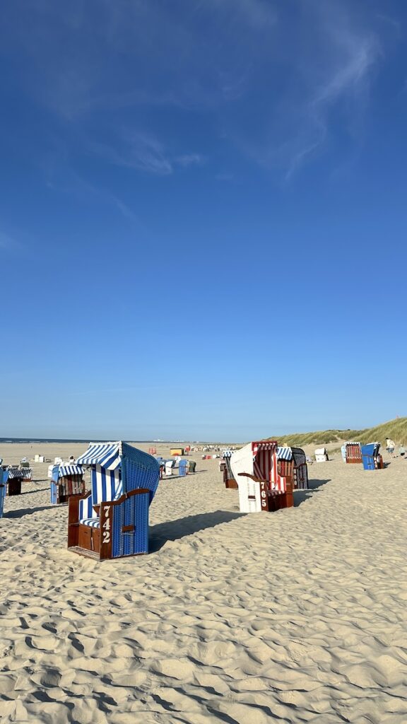 Der erste Blick auf den Strand nach der Ankunft auf Juist. Strahlend blauer Himmel und Strandkörbe in allen möglichen Farben