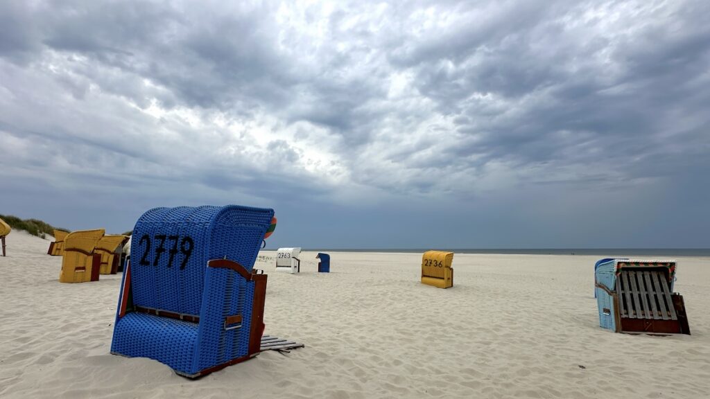 Wolkenverhangener Himmel und heller Sand mit bunten Standkörben. Ein schöner Kontrast