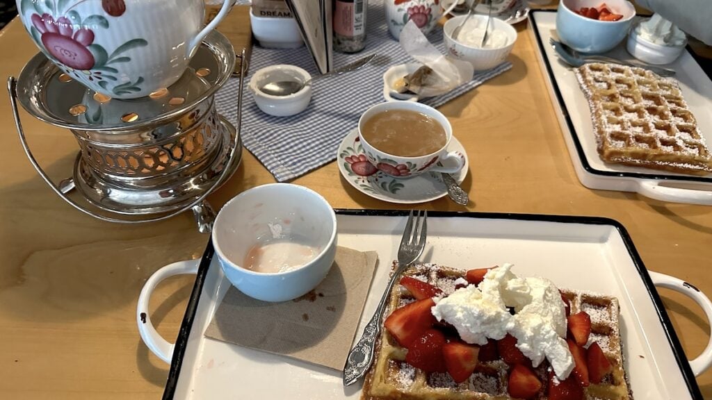 Waffel mit Erdbeeren und Sahne, dazu ein Kännchen Ostfriesenmischung auf dem Stövchen