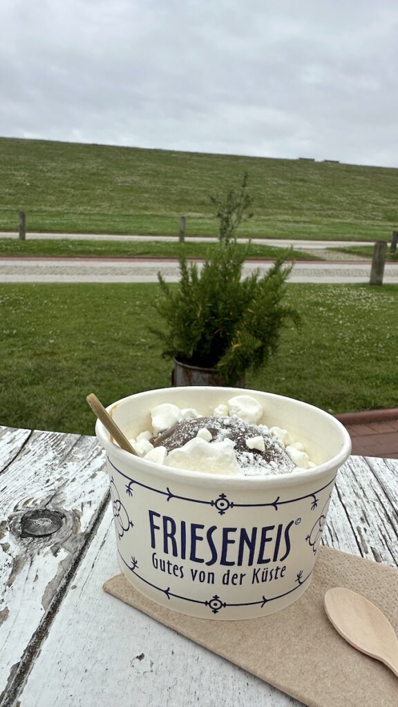 Eine riesengroße Kugel Eis im Becher mit Karamellsoße und Baiser-Topping
