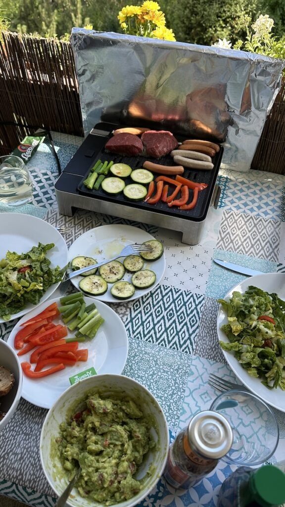 Elektrogrillen auf dem Balkon mit Fleisch, Wurst und Gemüse
